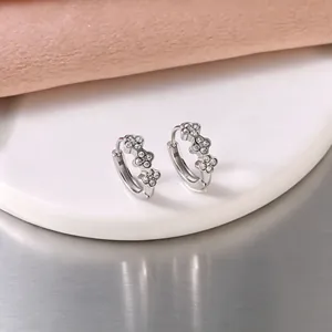 Close-up of stainless steel hoop earrings with delicate flower pattern set with crystals.