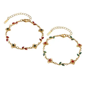 Close-up of gold stainless steel bracelets with red and green flower leaf charms