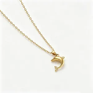Detalle de un collar con colgante de delfín minimalista en acero inoxidable dorado mujer