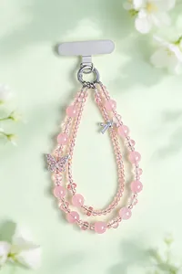 Dettaglio macro di un ciondolo per telefono a doppio strato con perle di cristallo rosa e farfalla