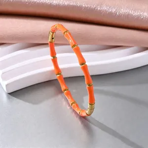 Nahaufnahme eines leuchtend orangefarbenen Edelstahl-Armband im Bambus-Stil für Damen