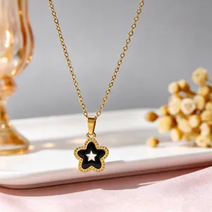 Close-up van gouden roestvrijstalen ketting met zwarte emaille holle ster hanger