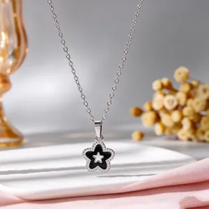Macrodetail van stervormige hanger met zwart email en een zilverkleurige ketting.