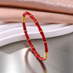 Detail van rood email en gouden bamboeschakels op de roestvrijstalen ring