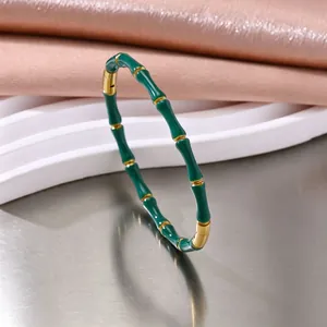 Detailopname van een luxe groene emaille bamboe schakelarmband met gouden accenten