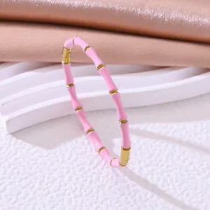 Close-up van een roze emaille en goudkleurige roestvrijstalen bamboe armband