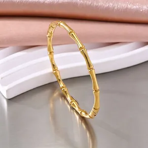 Detailopname van een goudkleurige roestvrijstalen armband in bamboestijl voor dames