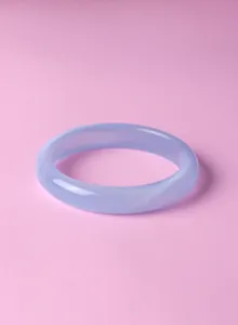 Detail view of a smooth lavender purple agate bangle on a soft pink background