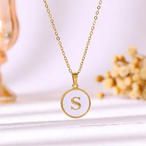 Vue détaillée d'un collier en acier doré avec pendentif en émail blanc lettre S.