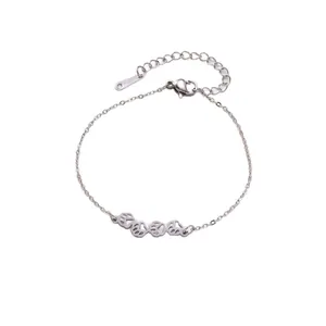 Primer plano de una pulsera de acero inoxidable plateada con cuatro dijes de huellas huecas