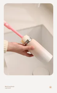 Detail view of a pink long-handle multifunctional cup brush cleaning the inside of a bottle