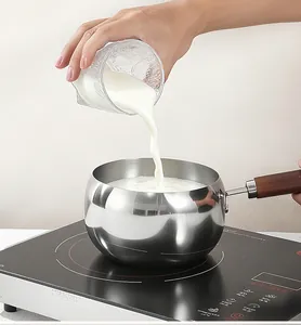 Detail van melk die in een roestvrijstalen pan op een inductiekookplaat wordt gegoten