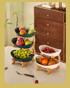 Close-up of tiered ceramic fruit bowls on a bamboo stand in a cozy kitchen setting.
