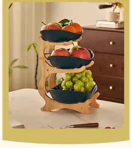 Three-tier natural bamboo fruit stand with dark green ceramic bowls and fresh fruits