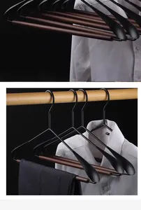 Detail view of luxury wide-shoulder metal clothes hangers with dark wood accents