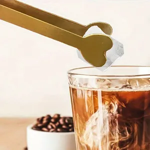 Premium golden stainless steel heart-shaped tongs picking up ice for a cold coffee