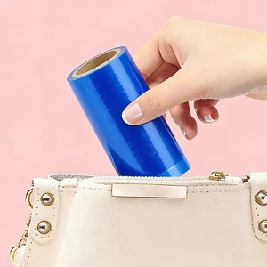 Tragbare blaue Einweg-Schutzfolienrolle, die in eine kleine beige Handtasche gesteckt wird.