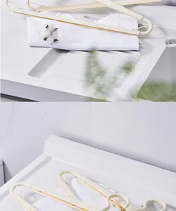 Détail des cintres rétractables crème sur une surface de blanchisserie blanche minimaliste.