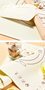 Macro detail of a cream silicone kneading mat with orange cat pattern and scale markings.