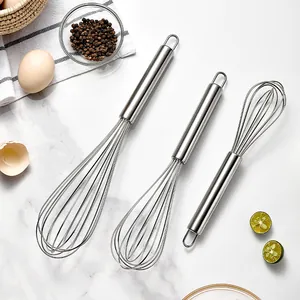 Professional set of three stainless steel whisks in different sizes on marble background
