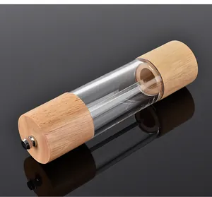 Detail view of the manual oak and acrylic pepper grinder on a reflective black surface.