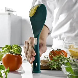 Green silicone rice paddle with smiley face held by a professional chef in kitchen