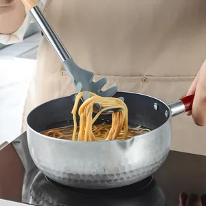 Grey silicone spaghetti server with ergonomic wooden handle lifting pasta from a pot