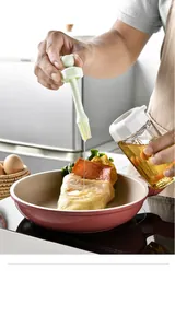 Close-up of hand using a silicone oil brush to apply oil on a crepe in a frying pan