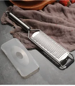 Primo piano di una grattugia per formaggio professionale in acciaio inox con coperchio protettivo