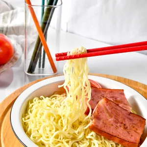 Rote Silikon-Essstäbchen halten Nudeln über einer Schüssel