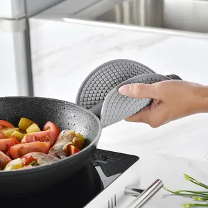 Grey round silicone heat insulation mat used as a non-slip pot holder in a kitchen scene