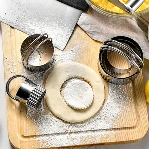 Stainless steel round biscuit cookie cutter set with handles on floured wooden board