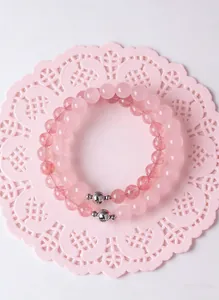 Close-up of pink rose quartz and strawberry quartz beaded bracelets on a lace mat