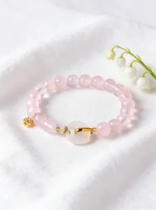 Detailed macro view of natural rose quartz beads and white agate peace buckle charm with gold accents.