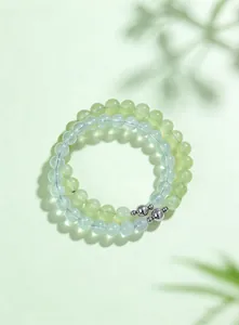 Detailed close-up of natural light green and blue crystal beaded bracelets with leaf shadows.