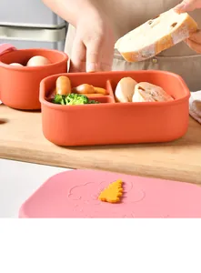 Gros plan d'une boîte bento en silicone avec compartiments alimentaires sur planche.