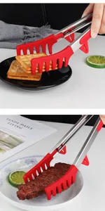 Detail view of red silicone comb-shaped food tongs picking up a steak and biscuits on plates.