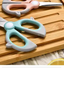 Detailed macro view of pastel-colored baby food scissors on a wooden cutting board