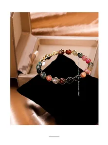 Close-up of a colorful tourmaline beaded bracelet with gold wire wrap and magnetic clasp.