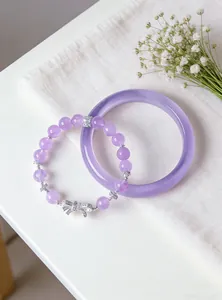 Close-up of a purple crystal beaded bracelet with bow charm and matching smooth bangle