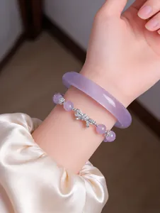 Close-up view of elegant lavender jade bangle and beaded butterfly knot bracelet on wrist