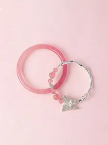 Close-up detail of a pink cat's eye stone bangle and silver butterfly charm beaded bracelet