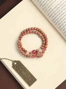 Macro view of natural cedarwood beaded bracelet with carved rose and strawberry quartz