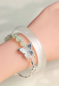 Detailed macro shot of an elegant butterfly crystal bracelet and cat-eye bangle stack.
