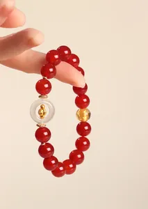 Detail view of a natural red agate beaded bracelet with a white safety buckle charm.