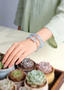 Detailed macro view of a silver butterfly charm bracelet and translucent cat eye stone bangle