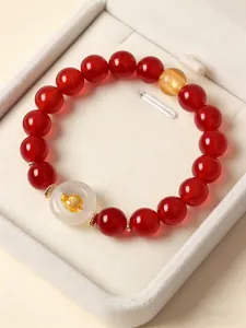 Detailed view of red agate beaded bracelet with white agate peace buckle and gold zodiac charm
