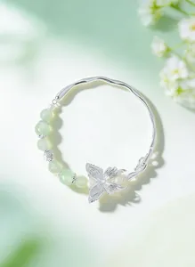 Detailed macro shot of an elegant silver butterfly and green crystal bead bracelet.