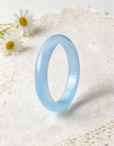 Detailed macro view of a light blue translucent quartz bangle on white lace background