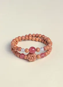 Detail of natural cypress wood beaded bracelet with strawberry quartz and carved rose